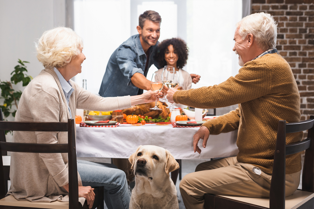 Golden Retriever sitting near multicultural family celebrating together at home