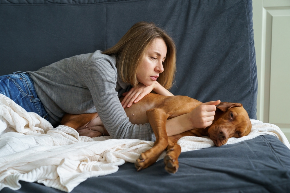 Worried woman caring for a weakening senior dog at home — geriatric pet care