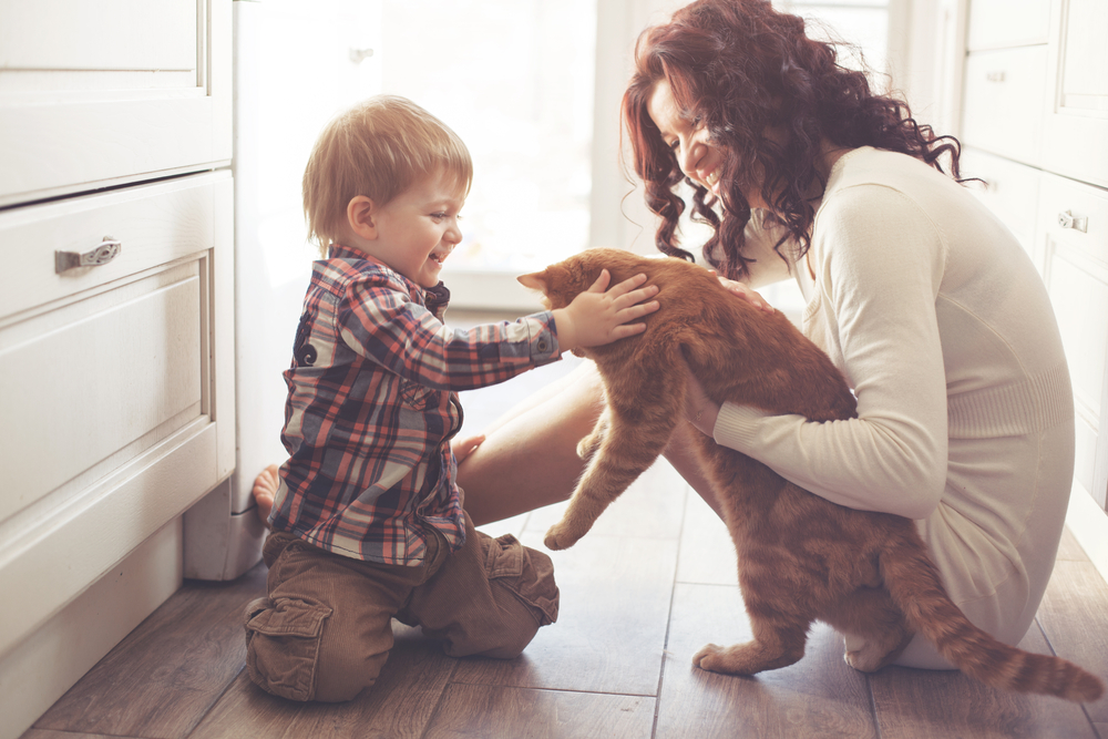 Mother and baby playing with their pet on the floor at home — family pet care in Wales, WI